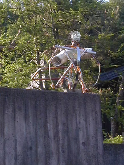 Burgdorfian — scrap-metal figure standing on a wall